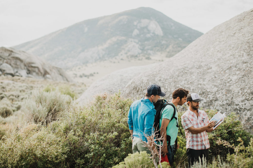 Kevin Jorgeson and Blake Mycoskie look over a guide book with local climbing guide Doug Workman.