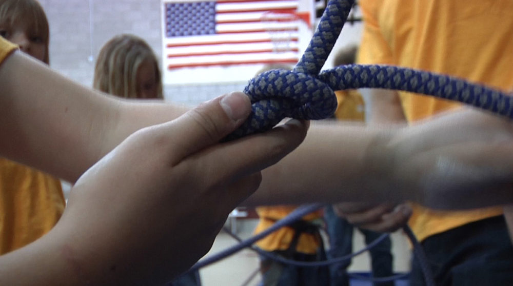 A Boys and Girls Club member ties a climbing rope.