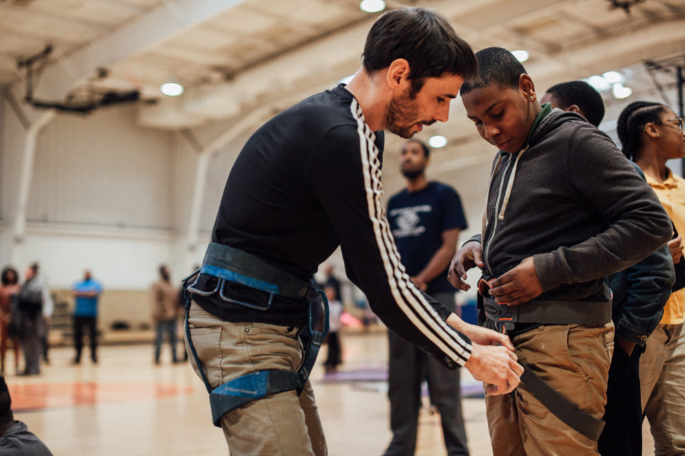 Kevin helps fit a climbing harness on a Boys and Girls club member.