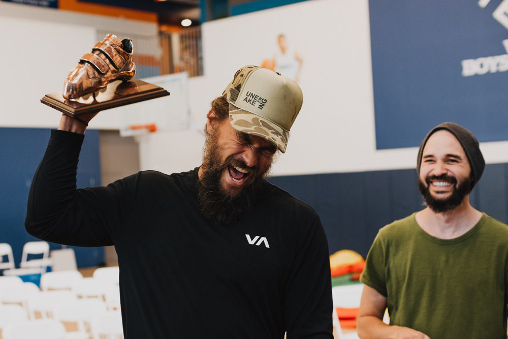 Jason Momoa receives a bronzed So iLL climbing shoe for his generous donation towards the new climbing wall.