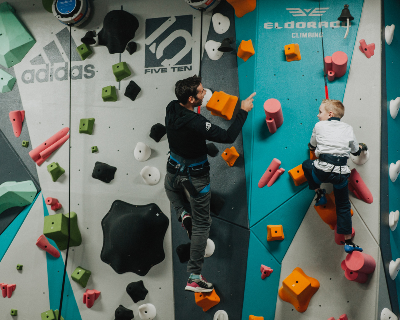 Kevin Jorgeson climbs on the 1climb wall with a boys and girls club member in santa rosa