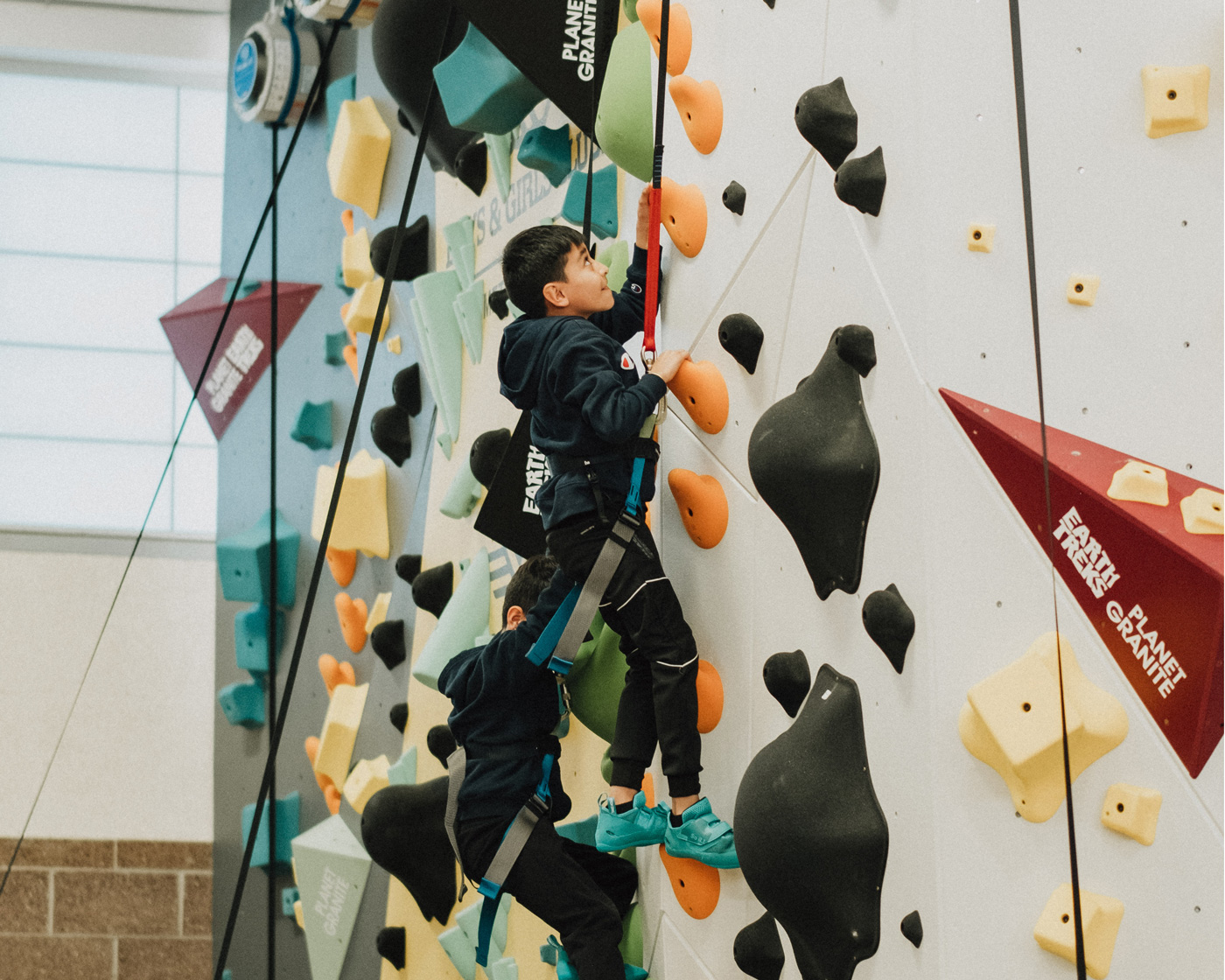 A boys and girls club member climbing up the new Denver 1Climb wall